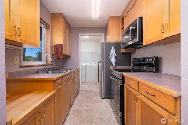 kitchen featuring a sink, separate washer and dryer, brown cabinetry, stainless steel appliances, and light floors