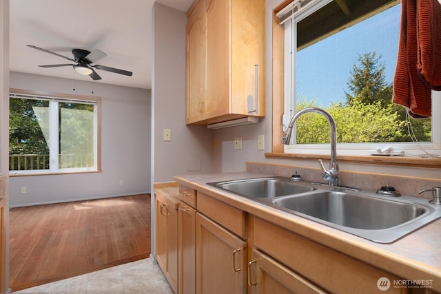 kitchen with light brown cabinets, ceiling fan, light countertops, a sink, and light wood finished floors
