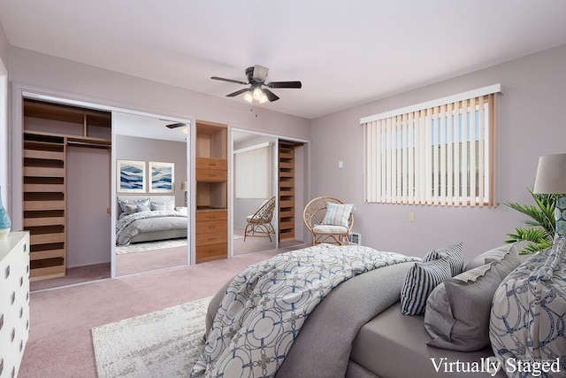carpeted bedroom featuring two closets and a ceiling fan