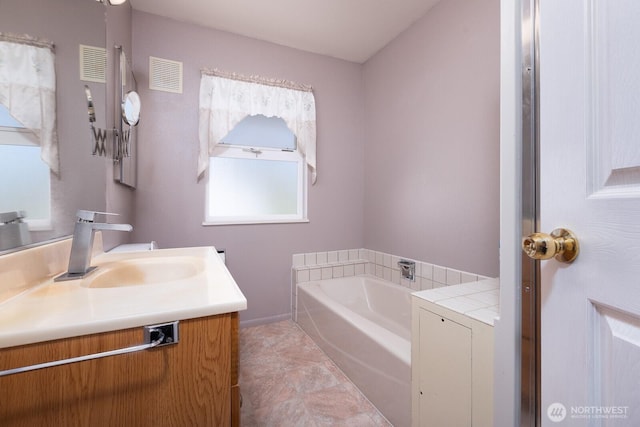 full bath featuring visible vents, a garden tub, and vanity
