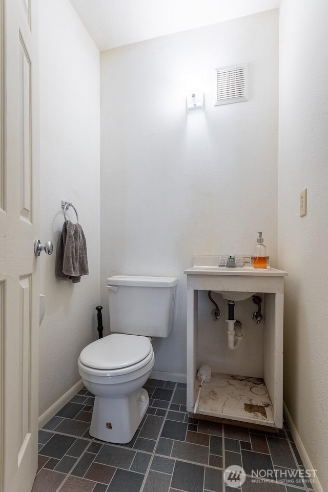 bathroom featuring toilet, baseboards, and visible vents