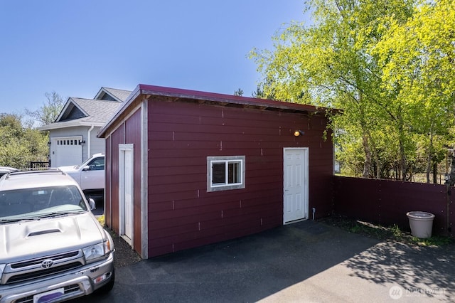 view of outdoor structure featuring a garage, fence, and an outdoor structure