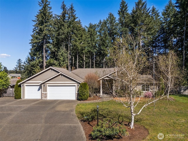 ranch-style home featuring a garage, stone siding, driveway, and a front yard