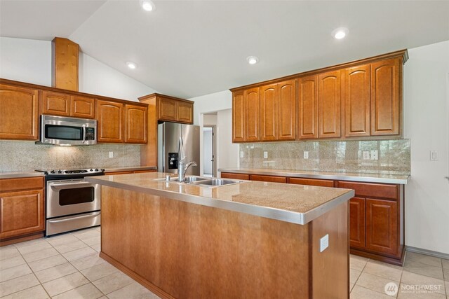 kitchen featuring a sink, light countertops, stainless steel appliances, light tile patterned flooring, and an island with sink