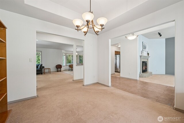 interior space featuring baseboards, a warm lit fireplace, and a chandelier