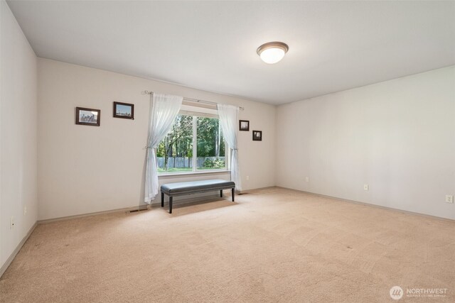 empty room featuring baseboards, light carpet, and visible vents