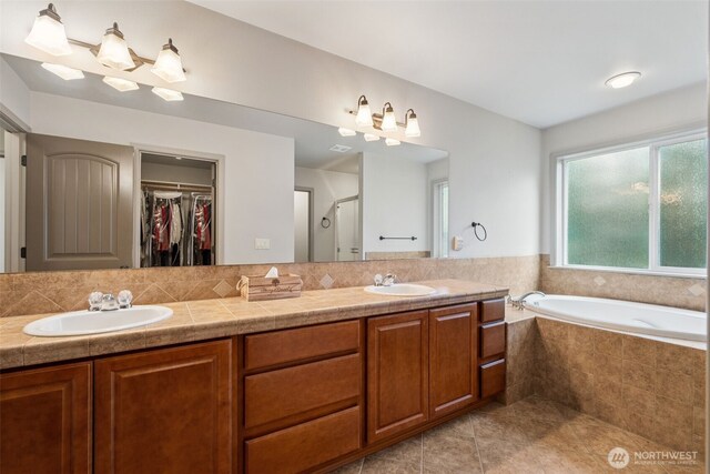 full bathroom with a sink, a walk in closet, a stall shower, and tile patterned floors