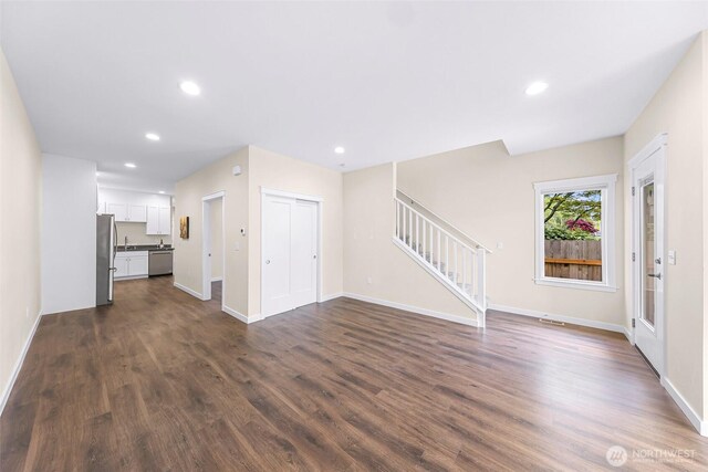 unfurnished living room with baseboards, stairs, and dark wood-style floors