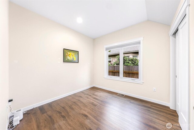 unfurnished bedroom with baseboards, visible vents, lofted ceiling, and dark wood-type flooring