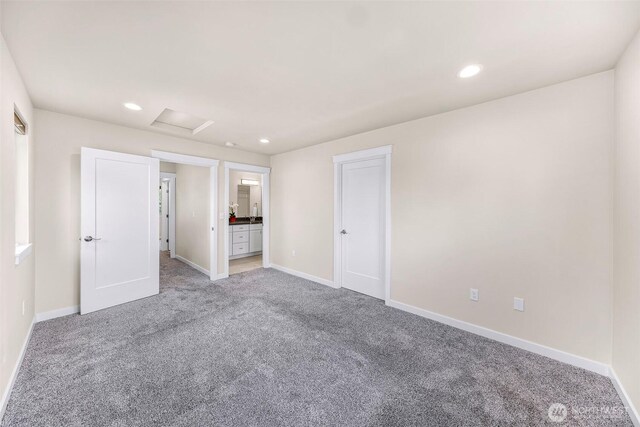 unfurnished bedroom with light carpet, baseboards, attic access, ensuite bathroom, and recessed lighting