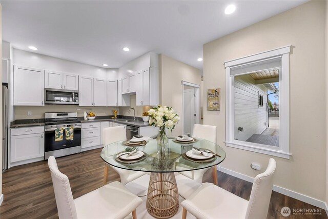 kitchen with a sink, white cabinets, dark countertops, and stainless steel appliances