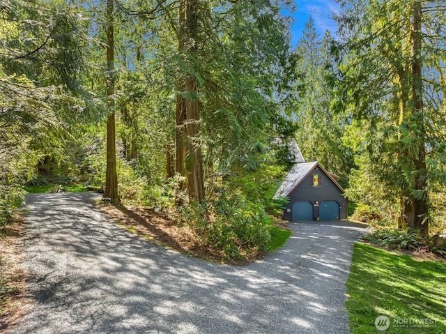 exterior space with a garage, an outbuilding, and a forest view