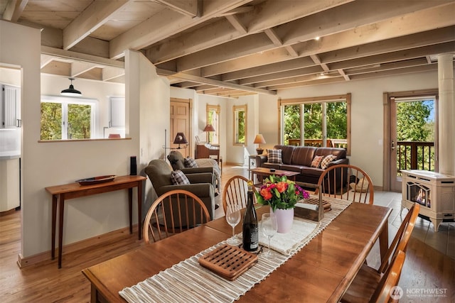 dining area with baseboards, a wood stove, wood finished floors, and beamed ceiling