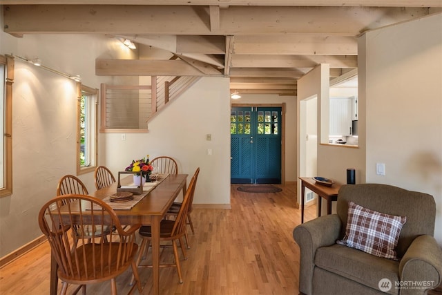 dining area with baseboards, beamed ceiling, a wealth of natural light, and light wood finished floors
