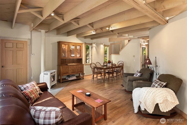 living area featuring light wood-style floors, a wood stove, ornate columns, and beam ceiling