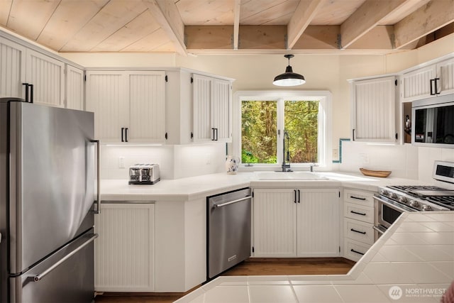 kitchen with a sink, backsplash, stainless steel appliances, and tile countertops