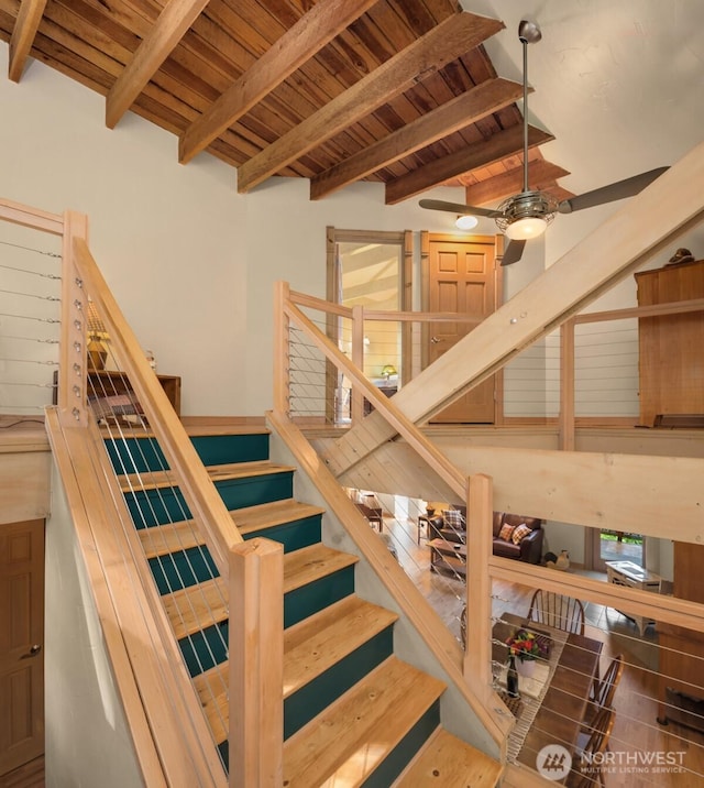 stairway featuring a ceiling fan, wooden ceiling, and beam ceiling
