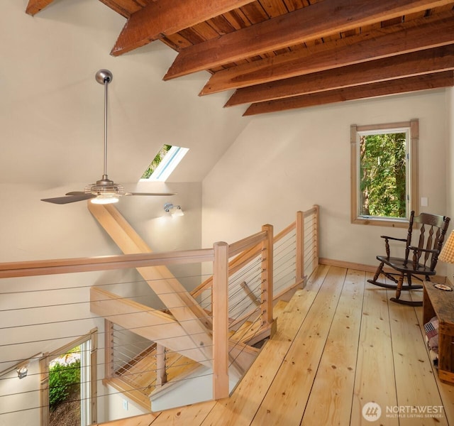 additional living space featuring baseboards, a ceiling fan, light wood-style flooring, and vaulted ceiling with skylight