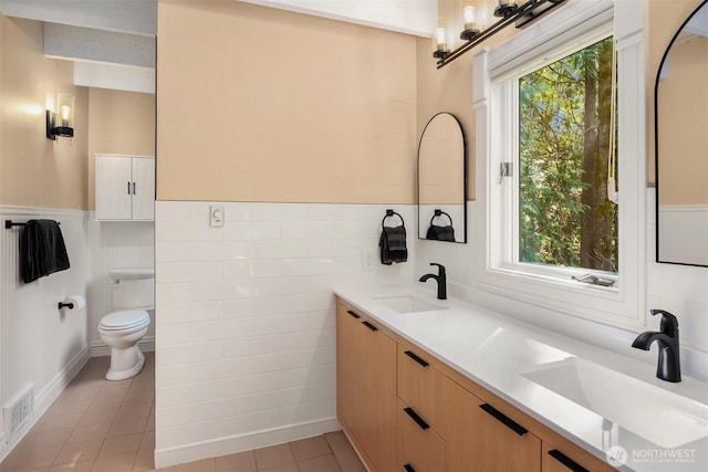bathroom with visible vents, wainscoting, a sink, and tile patterned flooring