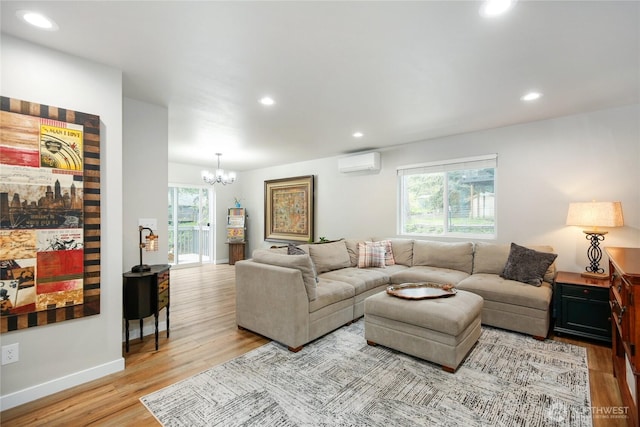 living room featuring an inviting chandelier, wood finished floors, a wall mounted AC, and a wealth of natural light