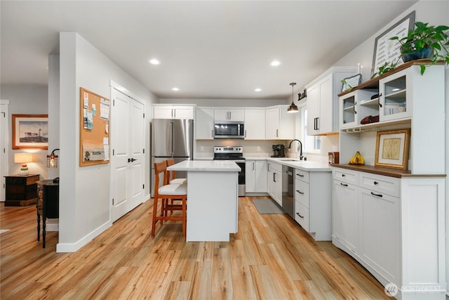 kitchen featuring a center island, stainless steel appliances, light wood-style flooring, and a breakfast bar area