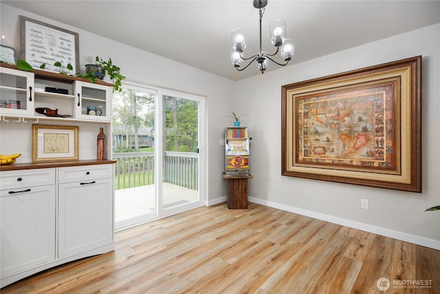 dining space with baseboards, a chandelier, and light wood-style flooring