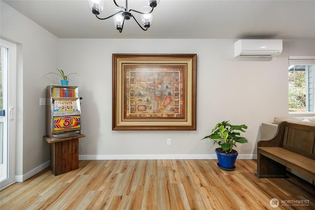 interior space featuring baseboards, a notable chandelier, wood finished floors, and a wall mounted AC