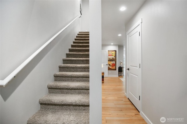 stairs with baseboards, wood finished floors, and recessed lighting