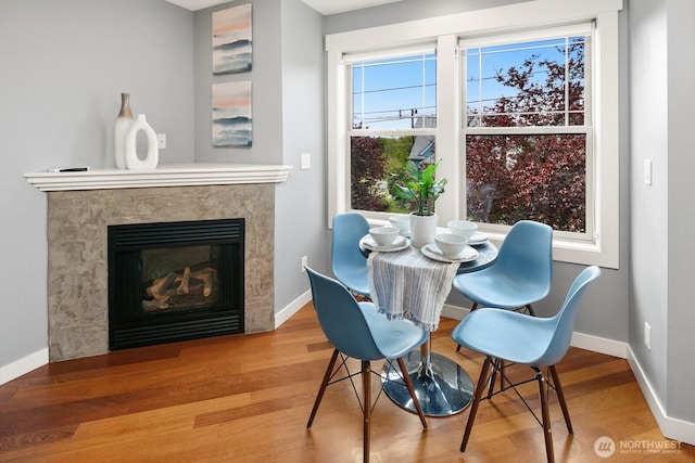 dining room with baseboards, wood finished floors, and a high end fireplace