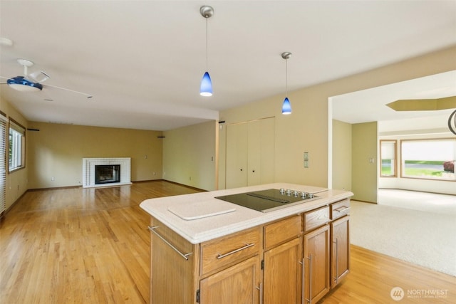 13233 W 44th Ave W, Mukilteo, WA 98275 - kitchen with black electric stovetop, open floor plan, light wood-style flooring, a brick fireplace, and a kitchen island