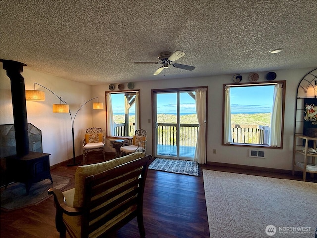 1311 Ocean Shores Blvd SW Unit 3, Ocean Shores, WA 98569 - living room with a wood stove, wood finished floors, ceiling fan, and a textured ceiling