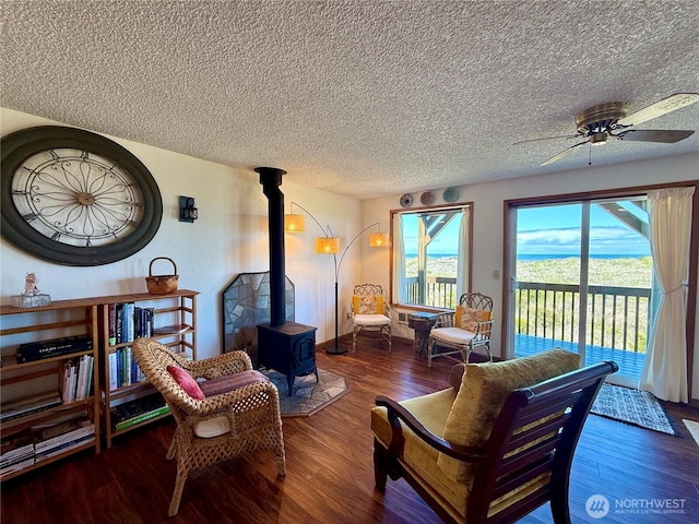 1311 Ocean Shores Blvd SW Unit 3, Ocean Shores, WA 98569 - living room with wood finished floors, a wood stove, a ceiling fan, and a textured ceiling
