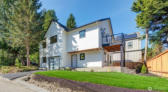 view of front of property with a garage, a balcony, asphalt driveway, and solar panels