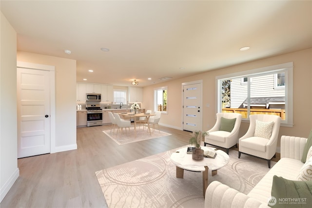 living area featuring baseboards, light wood-type flooring, and recessed lighting