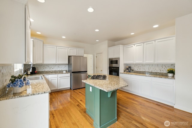 kitchen featuring white cabinets, light stone countertops, appliances with stainless steel finishes, decorative backsplash, and a kitchen island