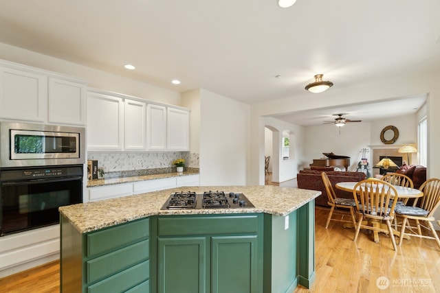 kitchen featuring decorative backsplash, a ceiling fan, arched walkways, black appliances, and white cabinetry