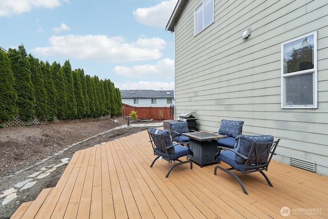 deck featuring fence, a fire pit, and visible vents