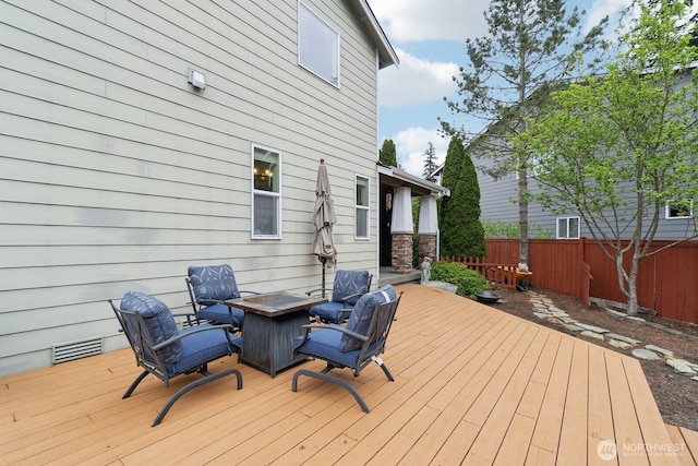 deck featuring fence, a fire pit, and visible vents