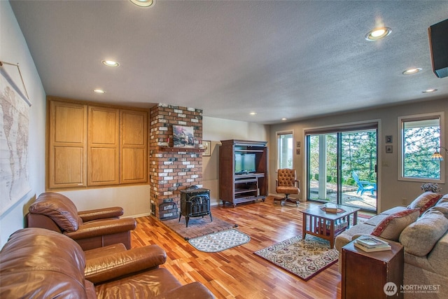 519 Highlands Dr, Orcas Island, WA 98245 - living room featuring a wood stove, recessed lighting, light wood-style floors, a textured ceiling, and baseboards