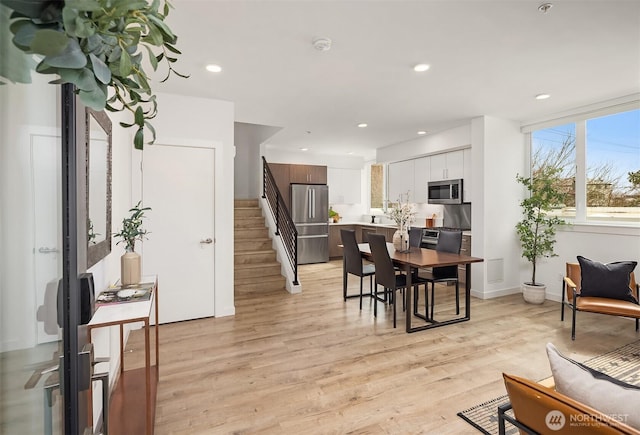 dining space with recessed lighting, baseboards, stairs, and light wood-type flooring