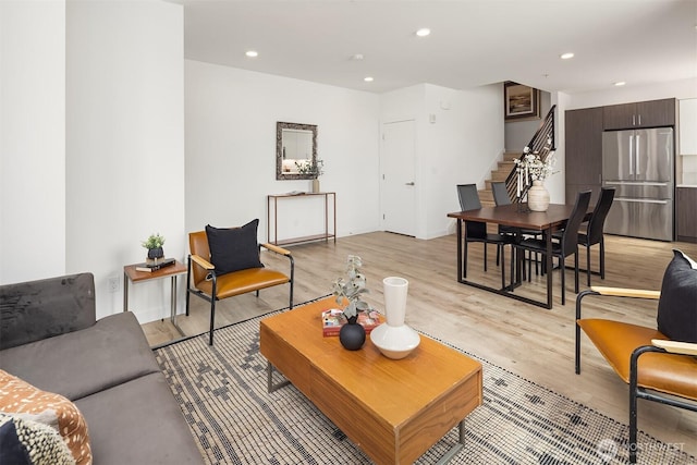 living area with recessed lighting, light wood finished floors, and stairs
