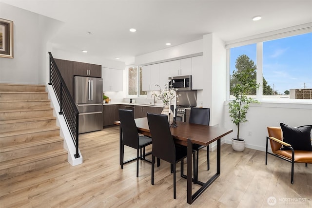 dining room featuring recessed lighting, light wood-style floors, baseboards, and stairs