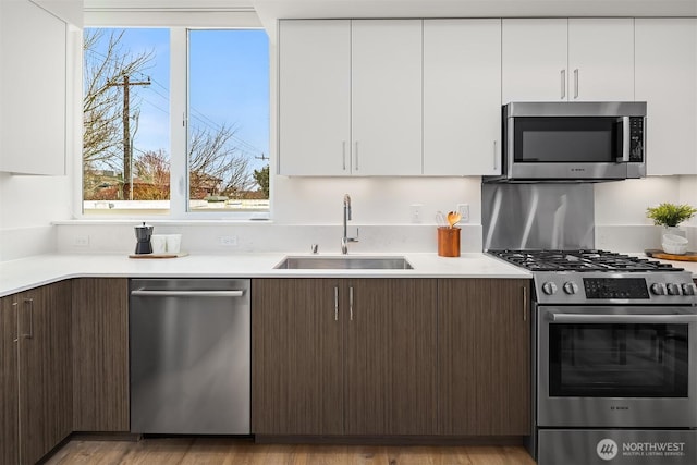 kitchen featuring white cabinets, light countertops, appliances with stainless steel finishes, and a sink