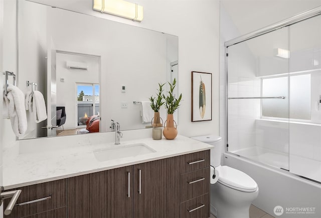bathroom featuring an AC wall unit, vanity, toilet, connected bathroom, and bath / shower combo with glass door