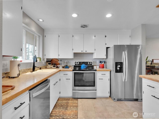 kitchen featuring white cabinets, stainless steel appliances, visible vents, and a sink
