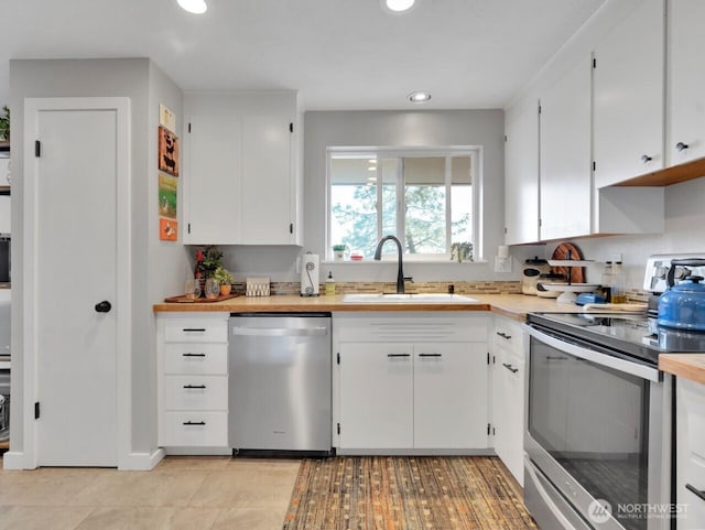 kitchen with white cabinets, recessed lighting, light countertops, a sink, and appliances with stainless steel finishes