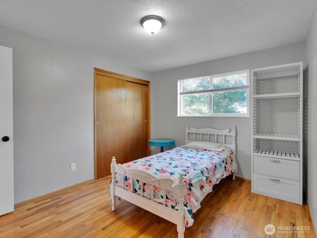 bedroom with light wood-style floors, a textured ceiling, and a closet