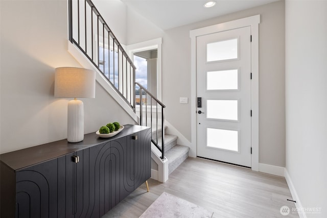 foyer entrance featuring light wood-style floors, baseboards, recessed lighting, and stairs