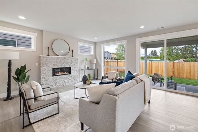 living area with baseboards, a stone fireplace, recessed lighting, and wood finished floors