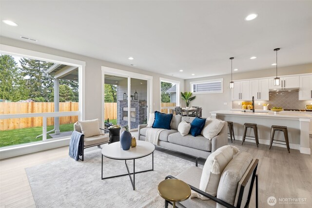 living room with recessed lighting, visible vents, and light wood-style flooring